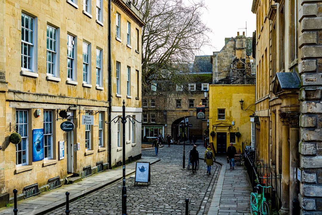 A cobblestoned side street in Bath, lined with honey-coloured Georgian buildings