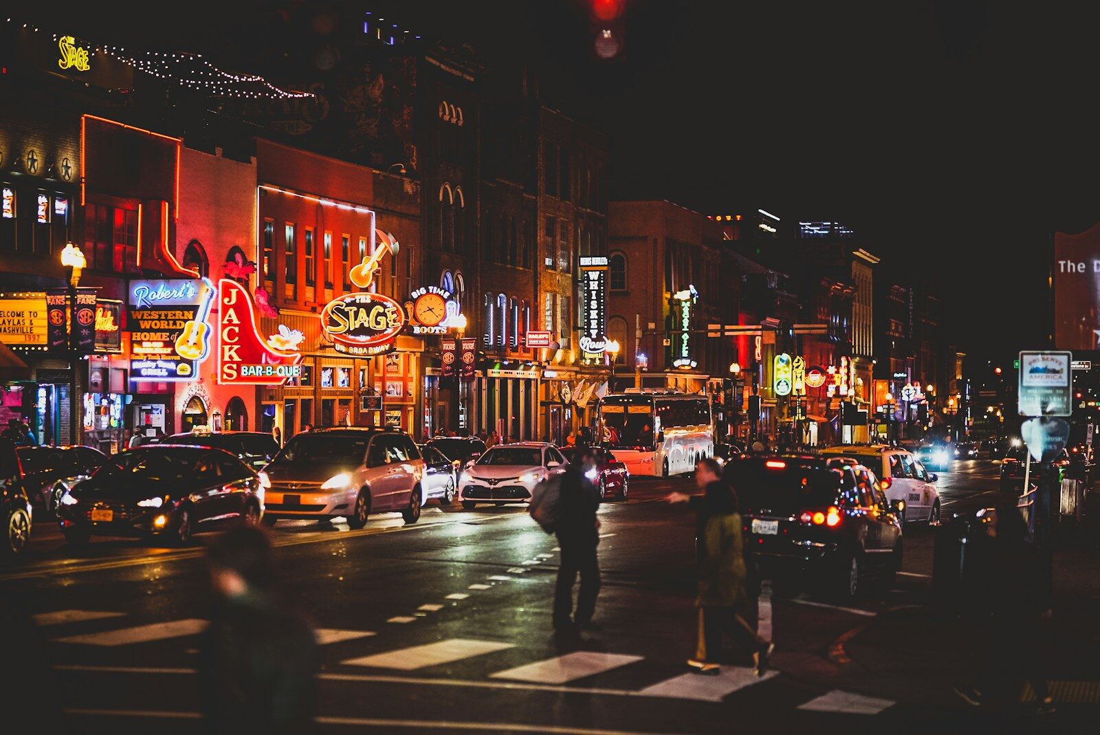 Lower Broadway Nashville at night with neon honky-tonk signs and pedestrians