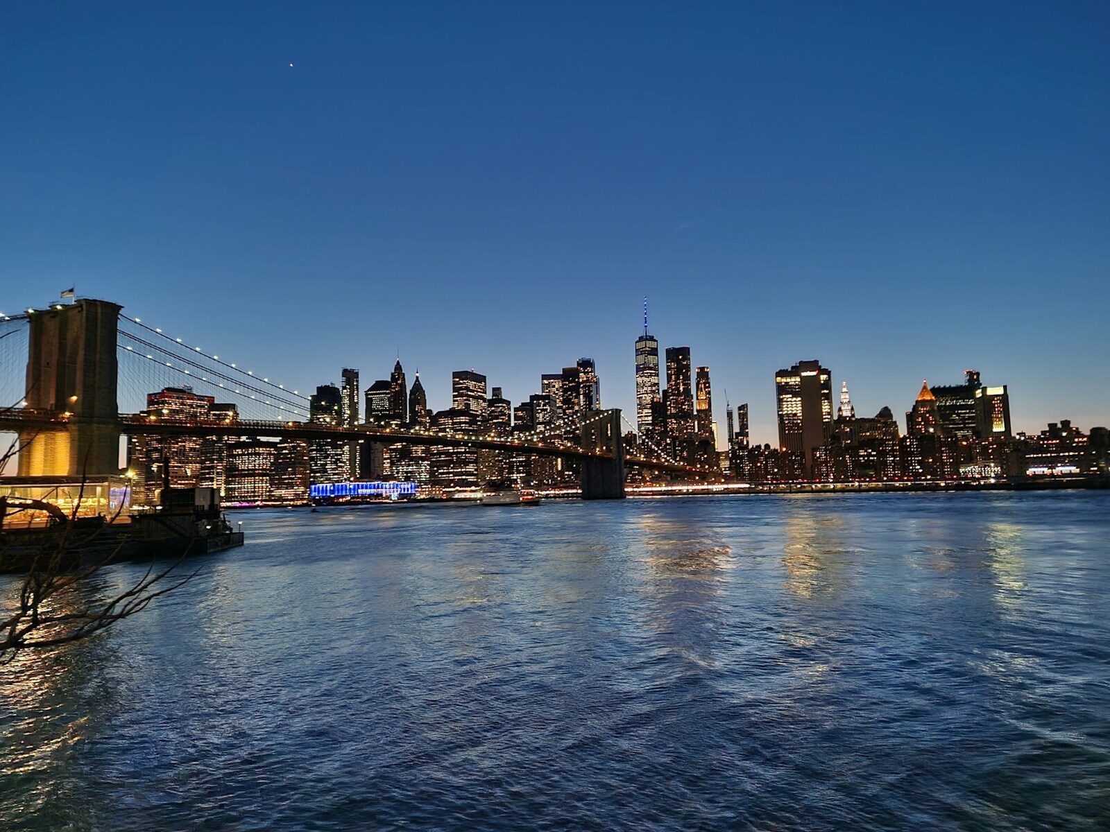 New York City skyline with Brooklyn Bridge at dusk in warm golden light